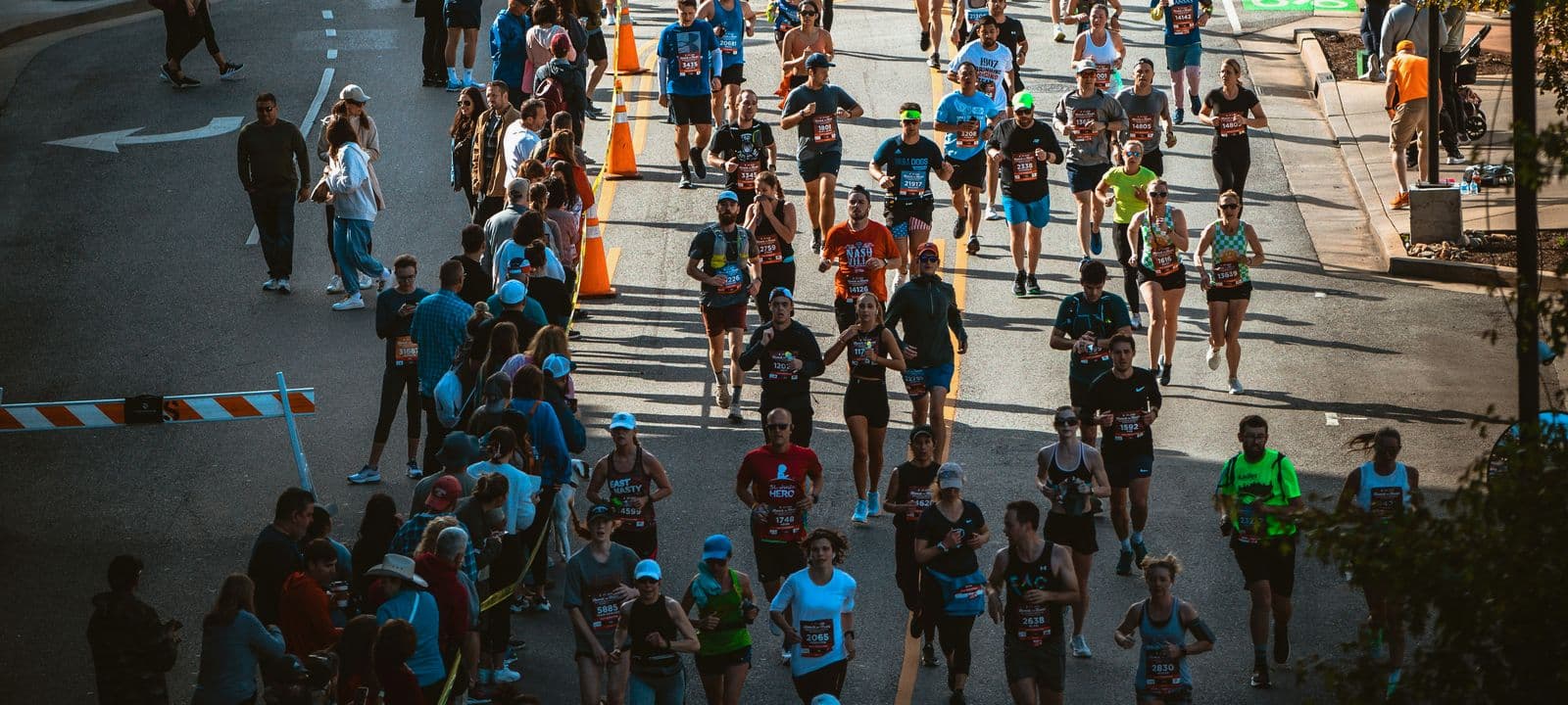 Runners on a closed city road during a run event, with traffic cones and crowd barriers managing the route. Event traffic management and road closure equipment rental in Malaysia.